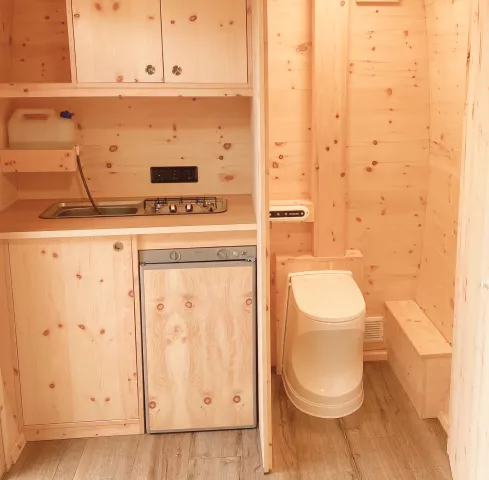 Küchen und Badabteil mit Kühlschrank, Frischwasser, Schränken, Spüle, Herd und abgetrennt links die Cinderella Toilette